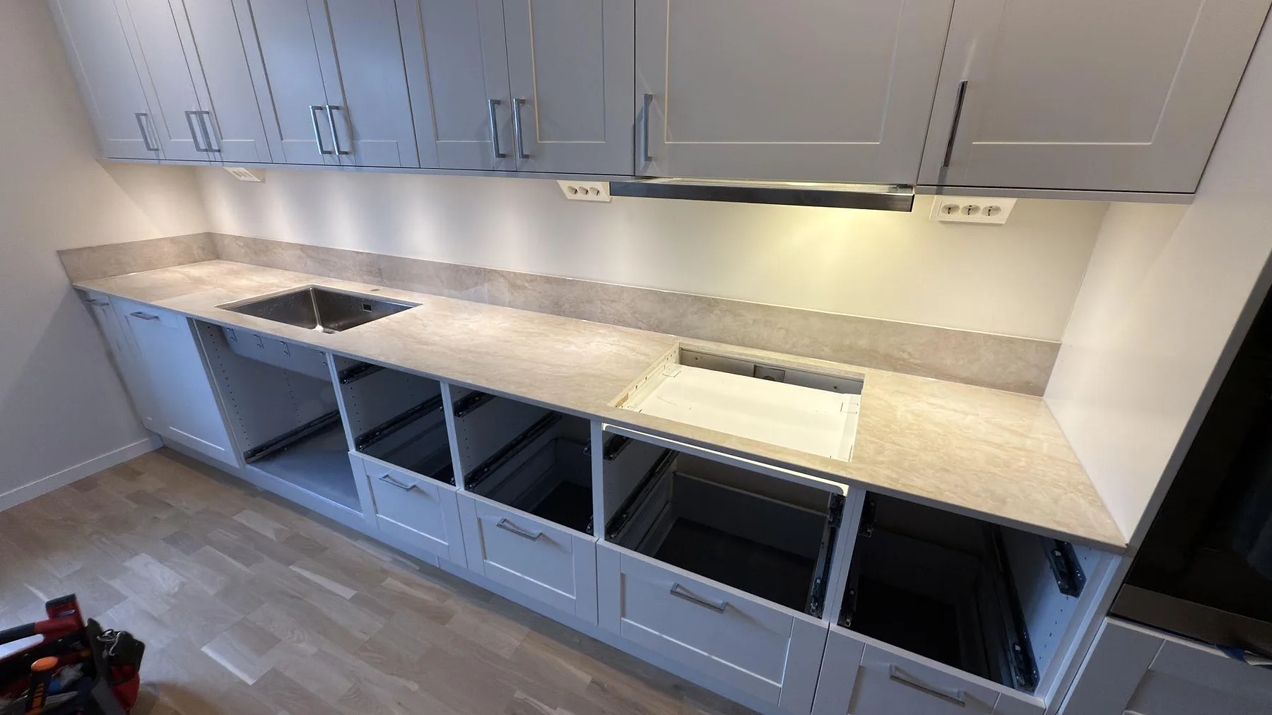 Bred vy över polerad Dekton Arga bänkskiva och låg stänkkant på raka köksstommar i Uppsala.