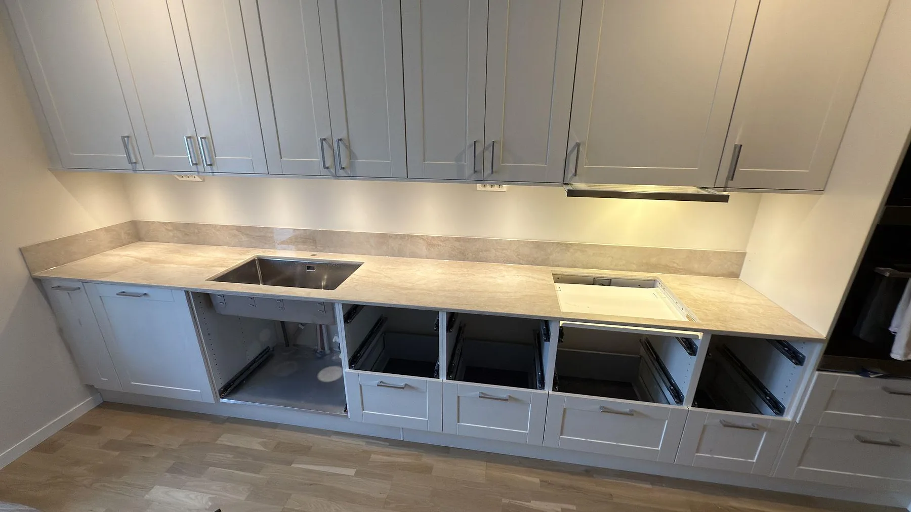 Köksbänkskiva i polerad Dekton Arga med stänkskydd i samma keramik i ett kök under montering i Uppsala.