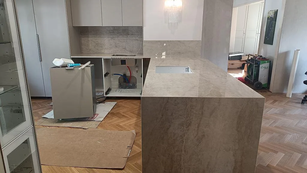 Köksbänkskiva och stor köksö i polerad Dekton Arga, 20 mm, med vattenfallsgavel och fiskbensparkett i ett kök i Vänersborg.