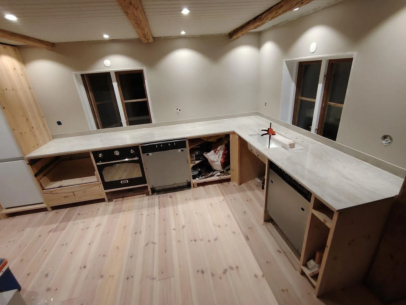 U-format kök i Vänge med polerad köksbänkskiva i Dekton Arga keramik, 20 mm, och matchande stänkskydd under montering.