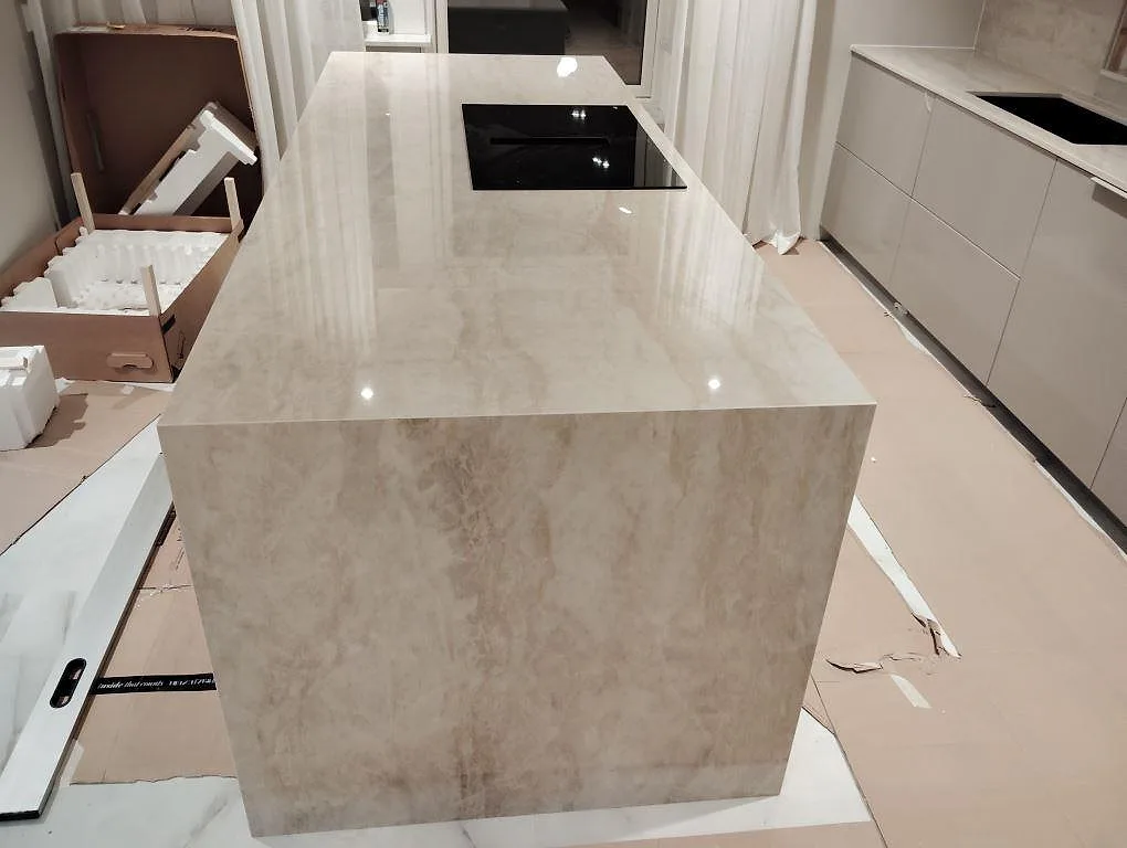 Polerad Dekton Arga på köksö med vattenfallsida och infälld häll under montering i Västerås.