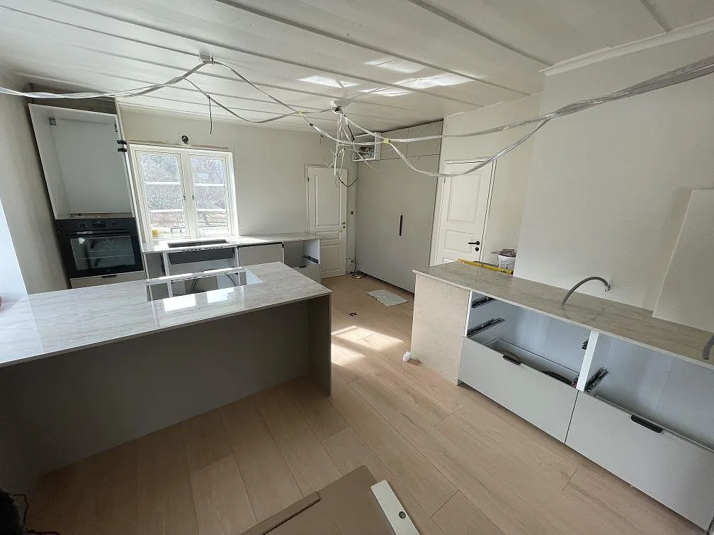 Köksbänkskiva i ljus polerad Dekton Arga, keramik, med köksö och väggbänk under montering i Västerås.