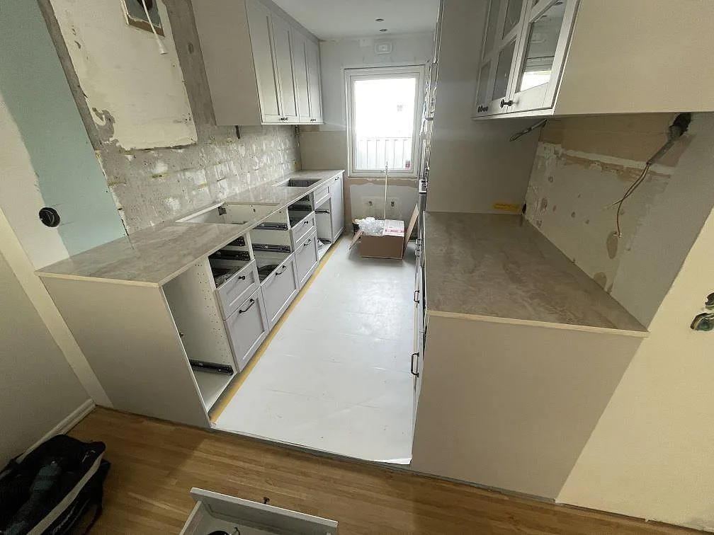 Köksbänkskiva i polerad Dekton Arga keramik med L-formad layout och vita köksstommar i Västra Frölunda.