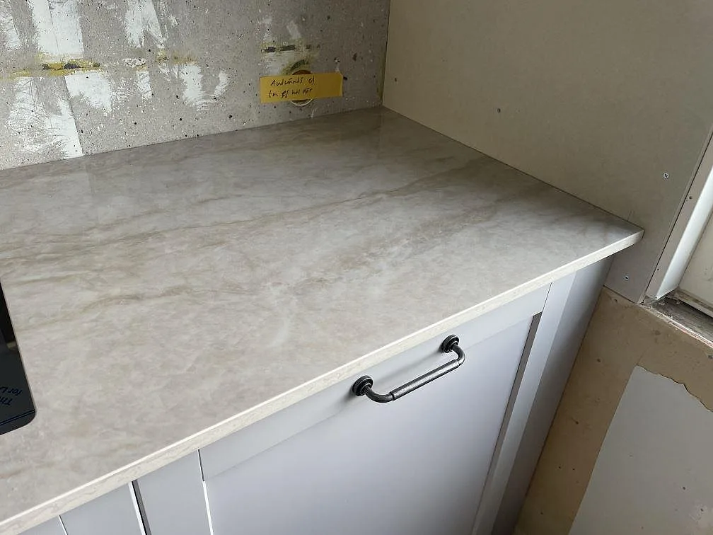 Detalj av polerad Dekton Arga bänkskiva med travertinliknande ådring vid kökets sidoyta i Västra Frölunda.