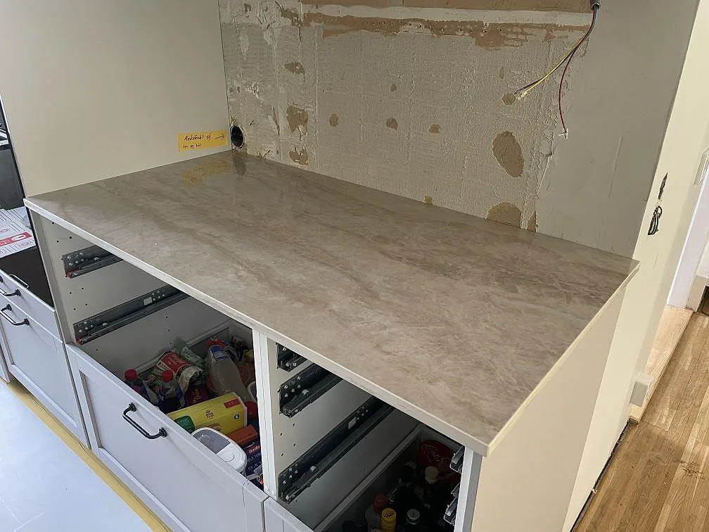 Rak arbetsyta i polerad Dekton Arga keramik ovanpå vita köksstommar under montering i Västra Frölunda.