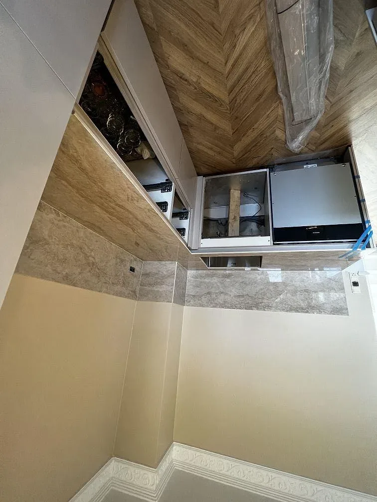 Köksrad i polerad Dekton Arga med stänkskydd och öppna stommar under pågående installation i Valby.