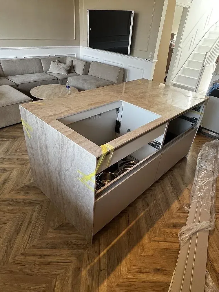 Köksö i Dekton Arga med krämvit marmorlik ådring och stäckt waterfall-kant, polerad sintrad sten i ett kök i Valby.