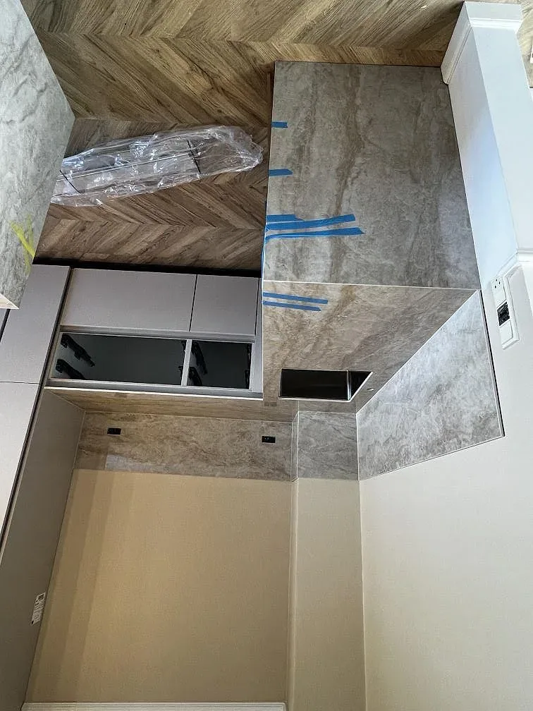 Köksbänkskiva och uppvikt stänkskydd i polerad Dekton Arga längs en köksvägg under montering i Valby.