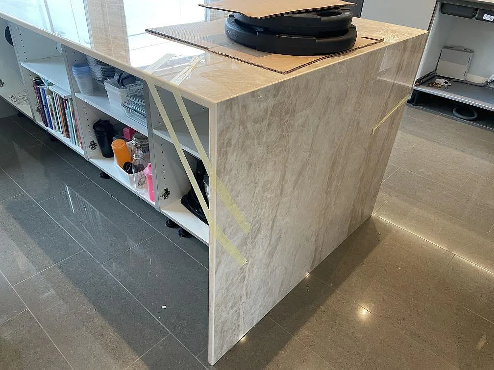 Köksö i polerad Dekton Arga, beige keramik med travertinlik ådring och stensida, i ett kök under montering i Veberöd.
