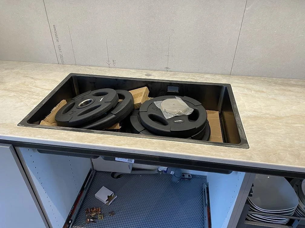 Mörk diskho i en köksbänkskiva av polerad Dekton Arga, beige keramik under montering i Veberöd.