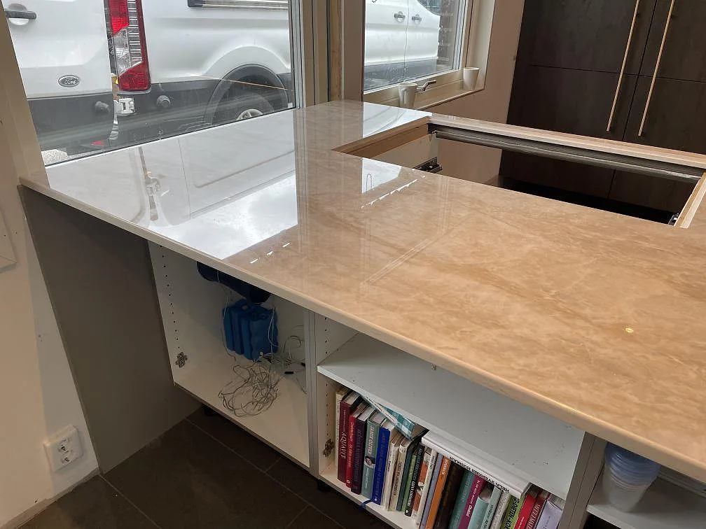 Polerad köksbänkskiva i Dekton Arga vid stora fönster, med förberedd öppning i ett kök under montering i Veberöd.