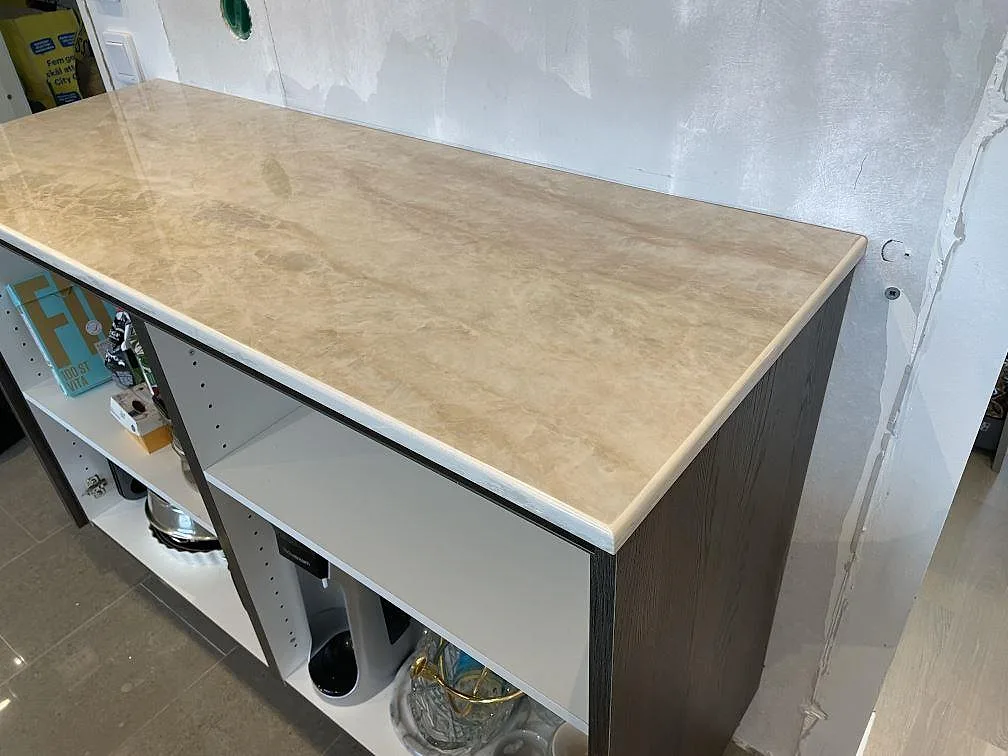 Installerad köksbänkskiva i polerad Dekton Arga, beige keramik över vita och mörka köksstommar i Veberöd.