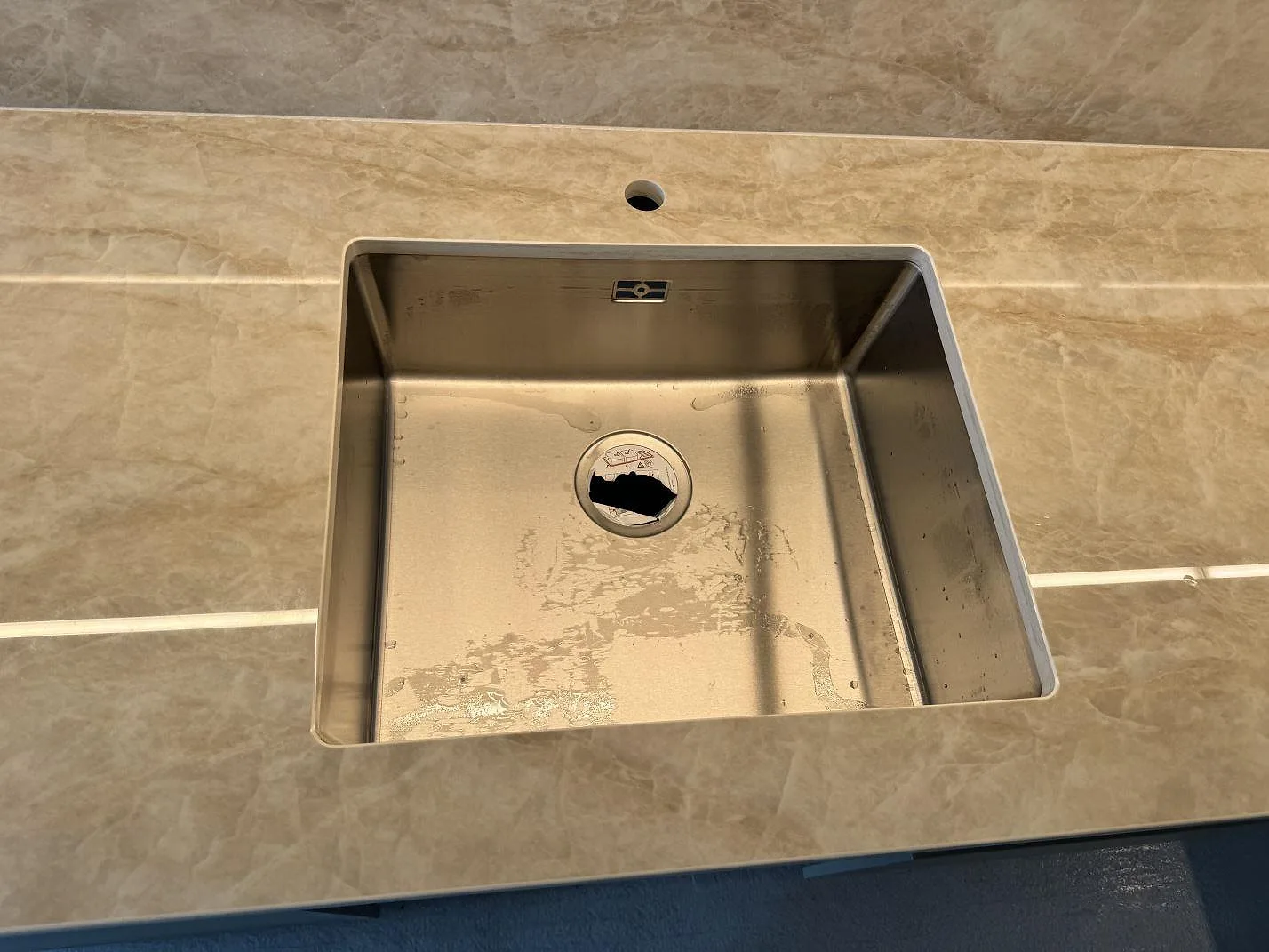 Närbild på polerad Dekton Arga kring diskhon, med gråbeige ådring och stänkskydd i köket i Ystad.