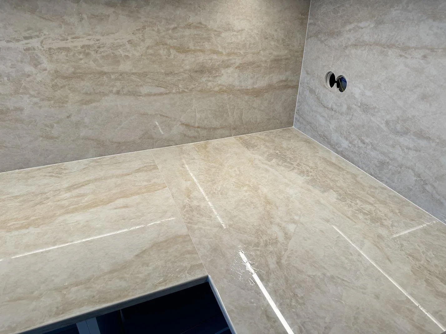 Detalj av polerad Dekton Arga i ett kök i Ystad, med bänkskiva, hörn och stänkskydd kring en öppen utskärning.