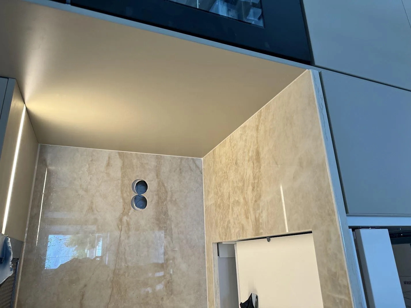 Vinklad detalj av polerad Dekton Arga i köket i Ystad, med stänkskydd, vägguttagshål och öppna köksstommar under montering.