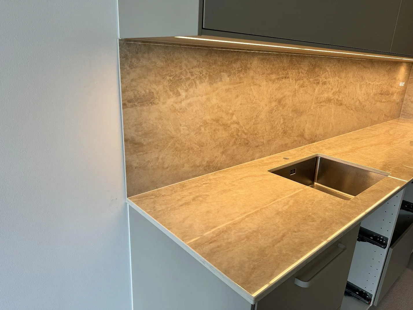Polerad köksbänkskiva i Dekton Arga med stänkskydd och synlig rostfri diskho i köket i Ystad.