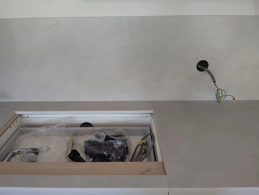 Grå matt Dekton Argentium som köksbänkskiva och stänkskydd runt diskzonen under montering i Sollentuna.