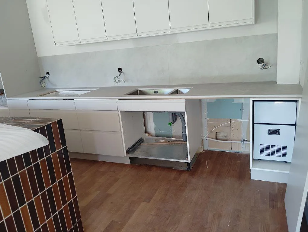 Köksbänkskiva i grå matt Dekton Argentium med dubbel underlimmad rostfri diskho och väggbeklädnad i ett kök i Sollentuna.