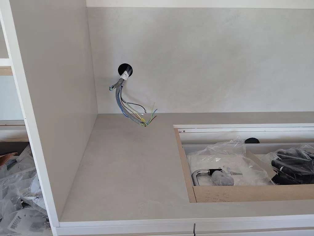 Köksbänkskiva i grå matt Dekton Argentium med sinkuttag och hög väggbeklädnad under montering i Sollentuna.