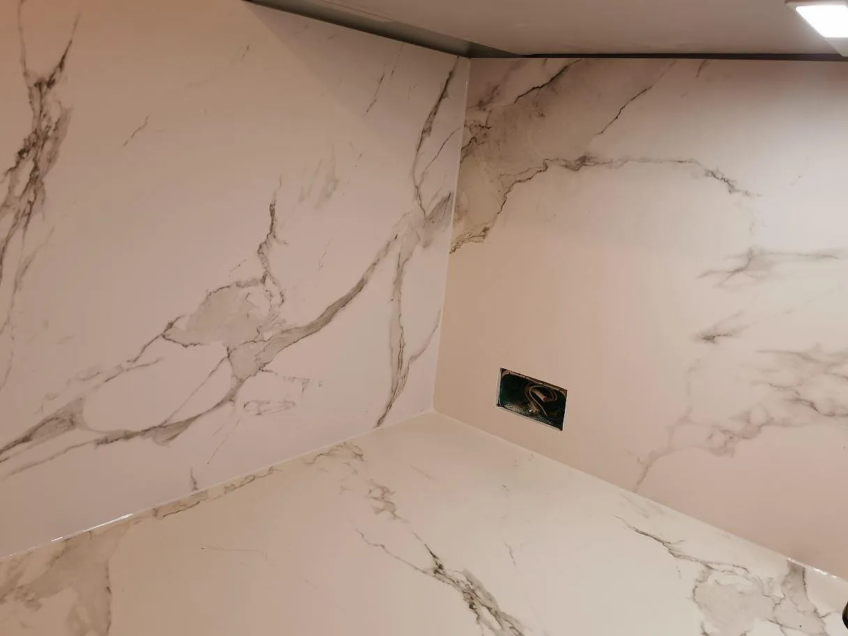 Hörndetalj av Dekton Aura 15 köksbänkskiva och heltäckande stänkvägg i marmorlik keramik i ett kök i Frederiksberg C.