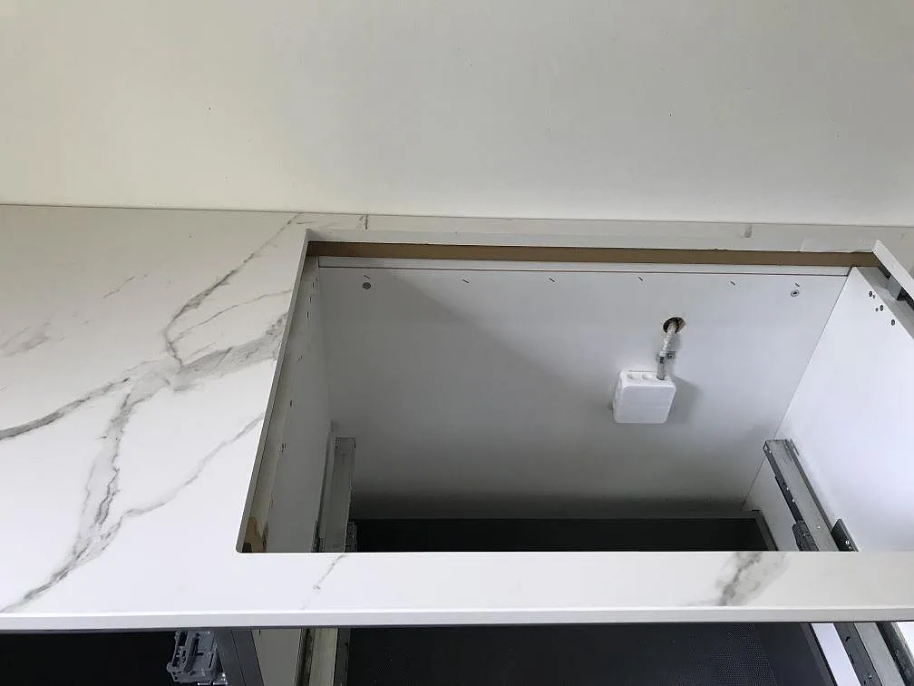 Köksbänkskiva i vit Dekton Aura 15 med urtag ned i underskåpet för installation av vitvaror i ett kök i Ølstykke.