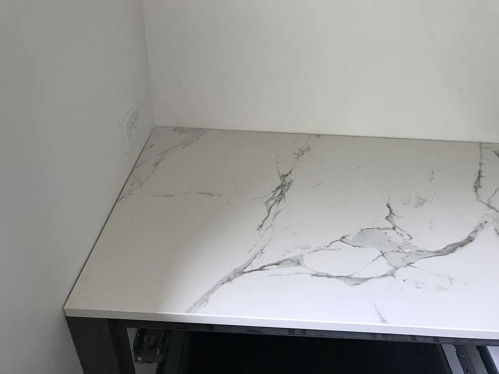 Köksbänkskiva i vit Dekton Aura 15, matt, mot vägg i ett kök under montering i Ølstykke.