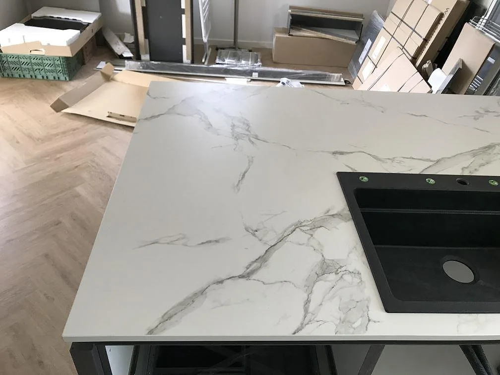 Köksbänkskiva i vit Dekton Aura 15, matt, med en svart kompositdiskho nedsänkt i bänkskivan i ett kök i Ølstykke.