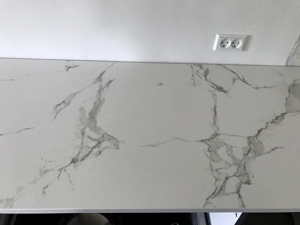 Köksbänkskiva i vit Dekton Aura 15, matt keramik med marmorlik grå ådring, vid eluttag i ett kök i Ølstykke.