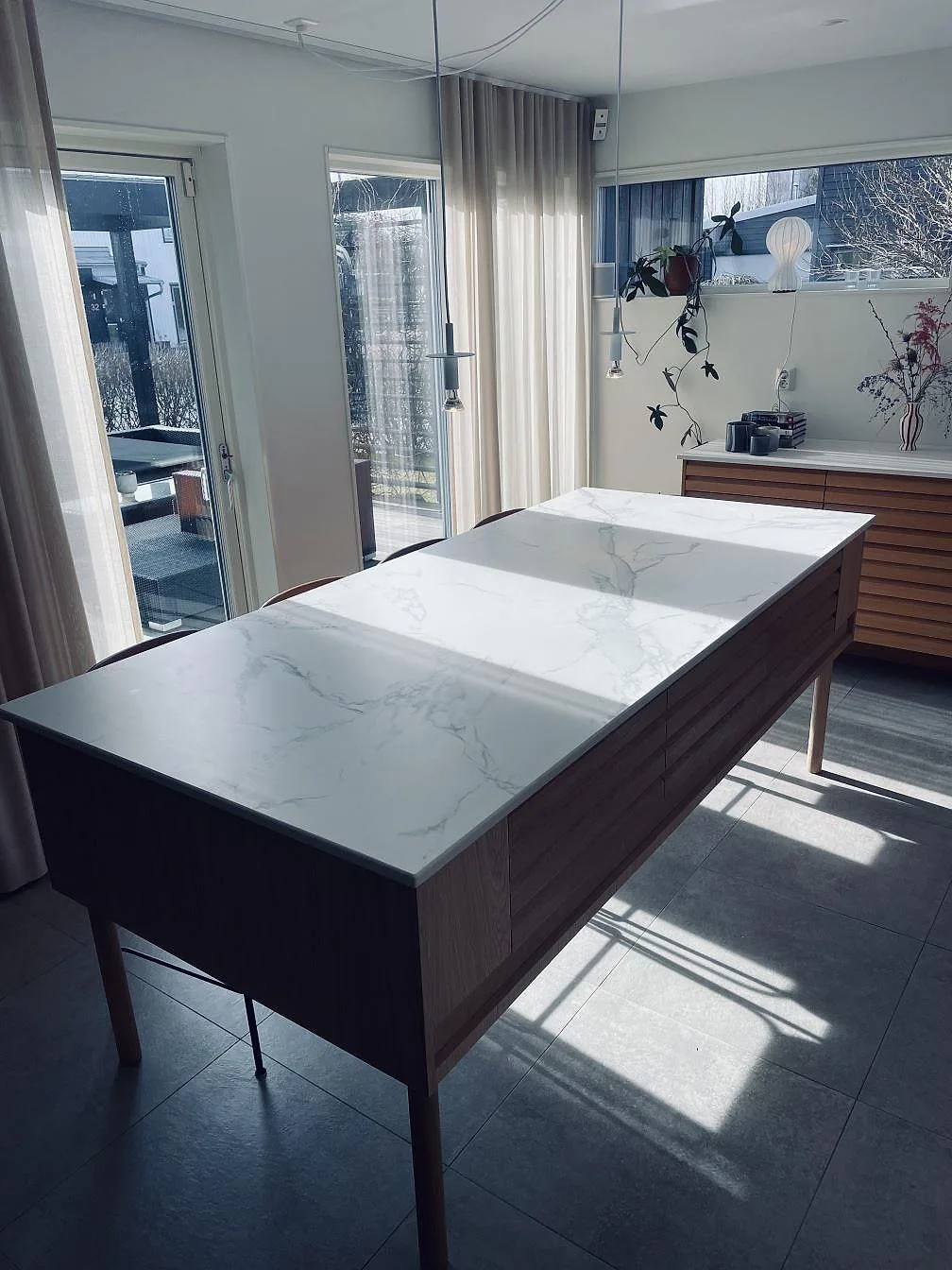Köksön i Dekton Aura 22 sedd från kortänden, matt vit keramik med grå ådring på ekfront, i ett kök i Falkenberg.