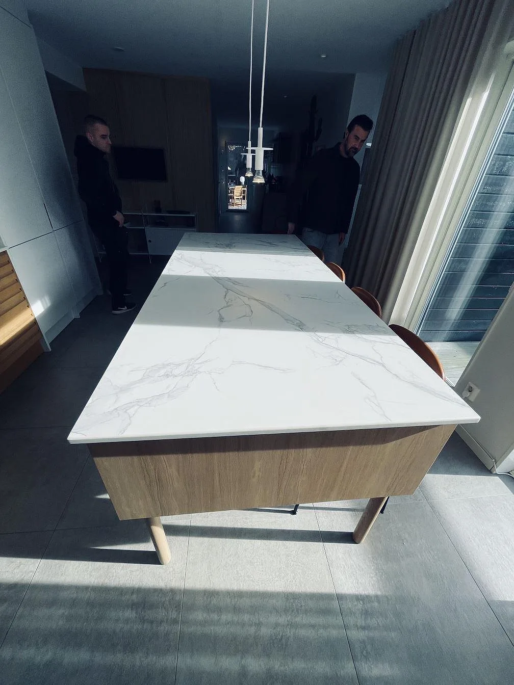 Köksö i Dekton Aura 22, vit keramikskiva med grå ådring i matt yta, i en ljus öppen köksmiljö i Falkenberg.