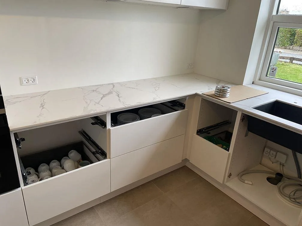Köksbänkskiva i matt Dekton Aura 22 längs vägg och fönster, med svart underlimmad diskho i Glostrup.