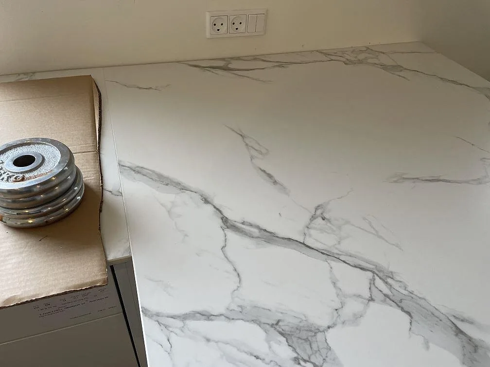 Ytdetalj av matt Dekton Aura 22 keramikbänkskiva med Calacatta-liknande ådring under montering i Glostrup.
