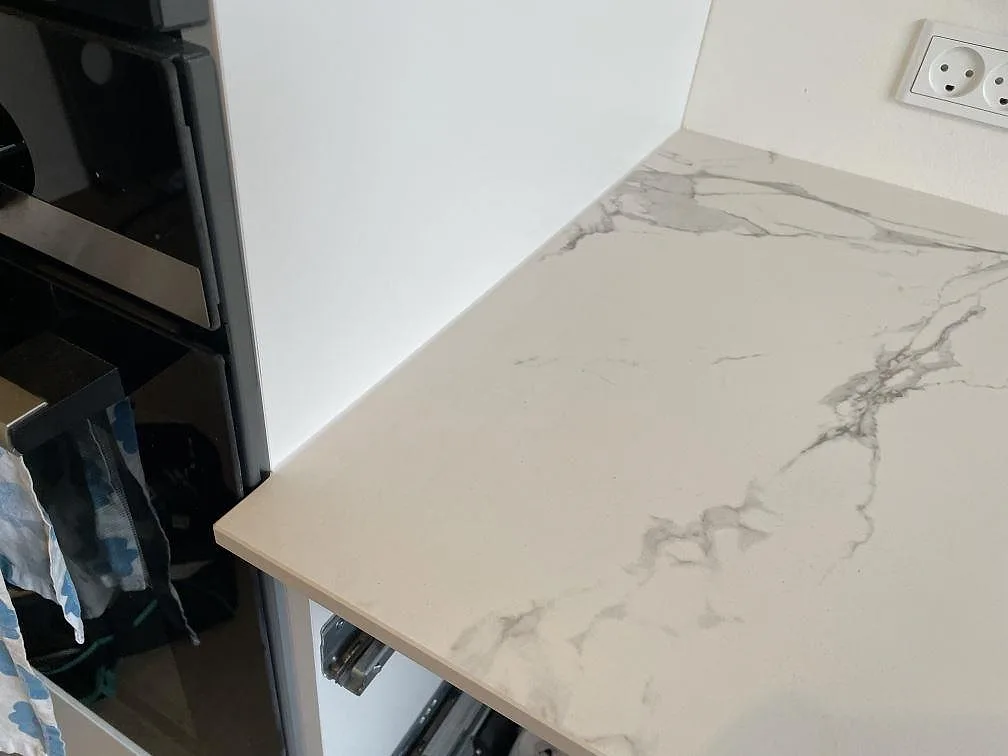 Närbild på kant och ådring i matt Dekton Aura 22 köksbänkskiva intill högskåp i Glostrup.