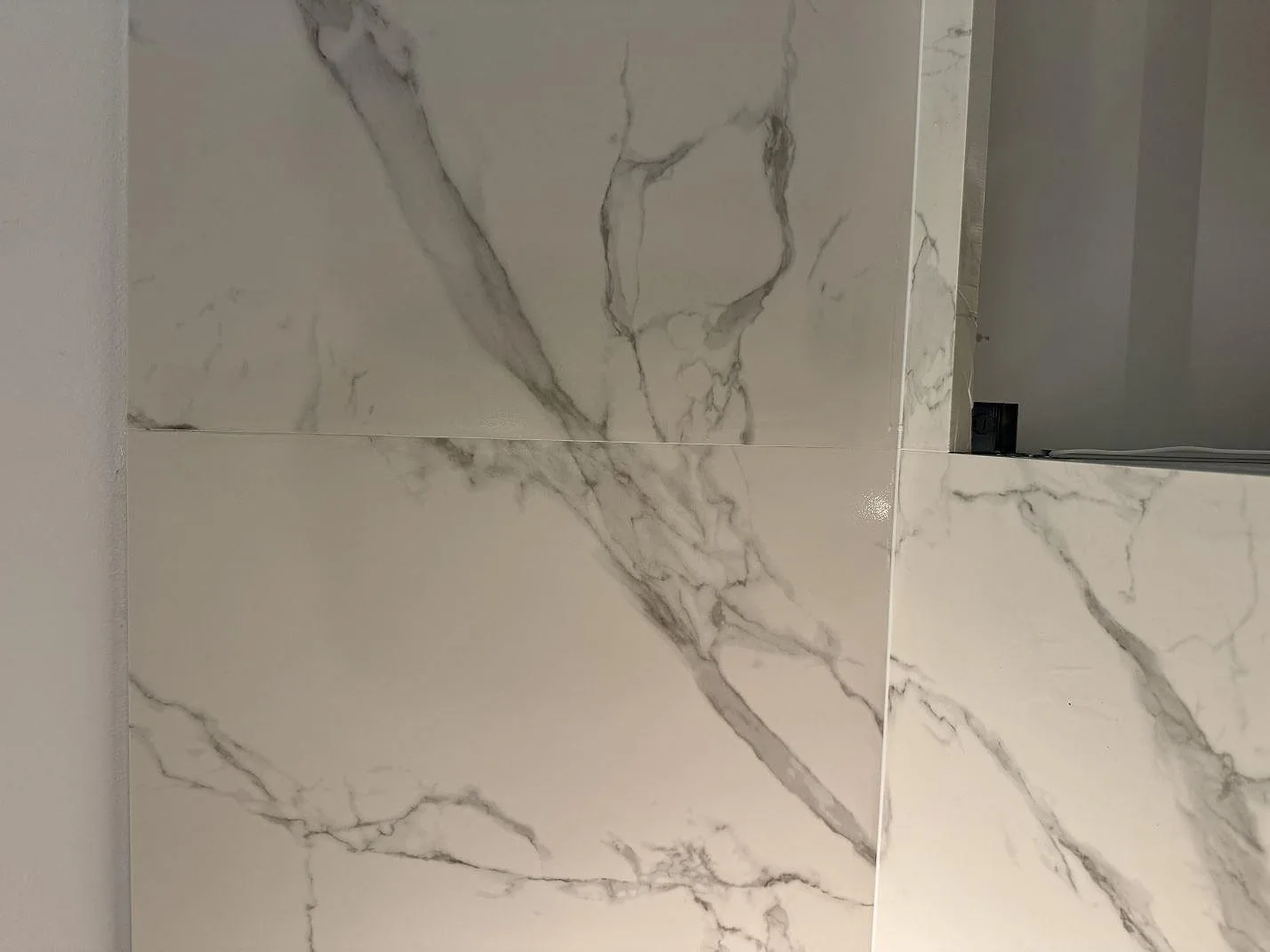 Detalj av ådrad väggbeklädnad och bänkskiva i matt keramik, Dekton Aura 22, i ett kök i Malmö.