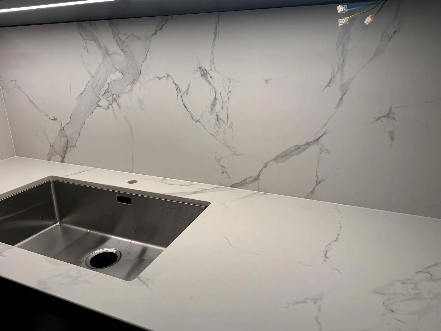 Närbild på matt Dekton Aura 22 i keramik som bänkskiva och stänkskydd vid en rostfri diskho i Malmö.