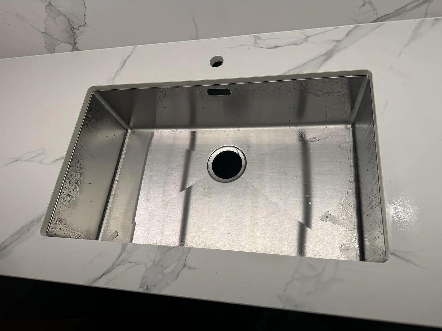 Detalj av rostfri diskho och kranhål i en matt köksbänkskiva av Dekton Aura 22 i Malmö.