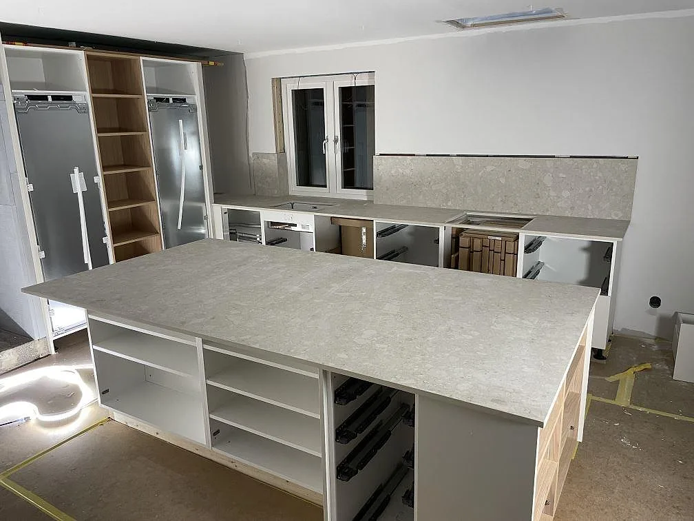 Köksbänkskiva och köksö i matt Dekton Ava i keramik i ett kök under montering i Djurmo.