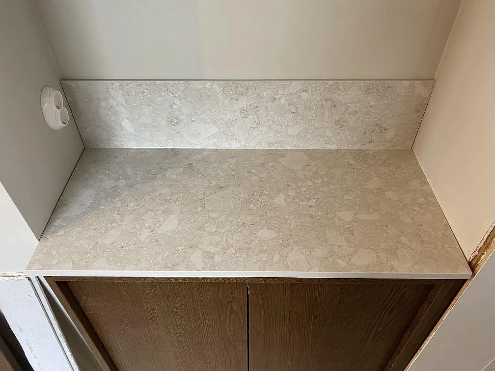 Sidobänk i matt Dekton Ava med lågt stänkskydd och ljus stenstruktur mot träinredning i Göteborg.