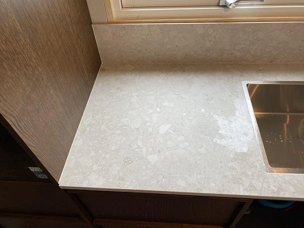 Närbild på ljus matt Dekton Ava runt diskhon, med träinredning och låg stänkkant i köket i Göteborg.