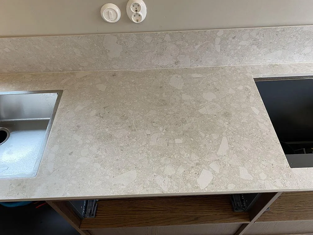 Detalj av matt Dekton Ava mellan rostfri diskho och hällöppning, med låg stänkkant i köket i Göteborg.
