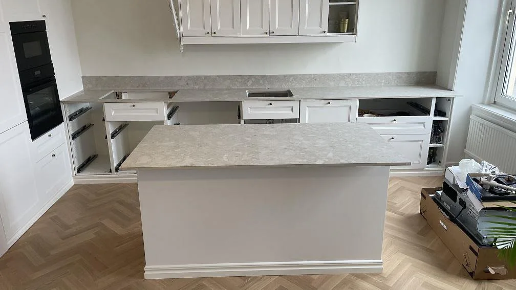 Köksbänkskiva och köksö i matt Dekton Ava, keramik, med låg stänkkant i ett kök i Göteborg under montering.