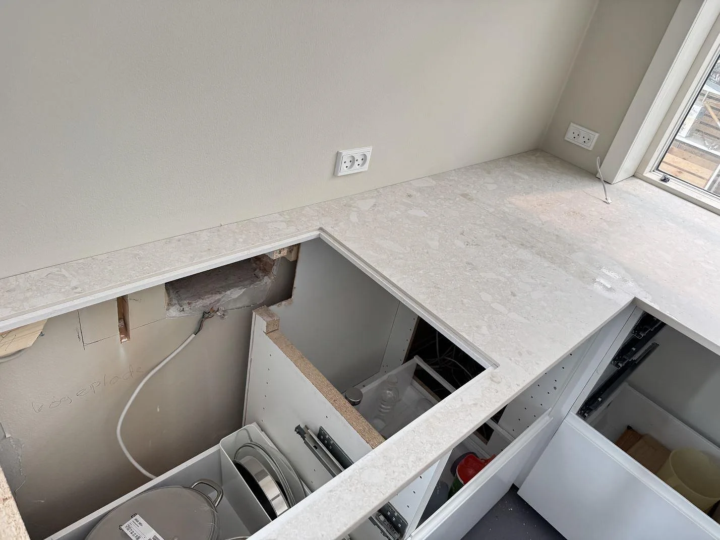 Vinkelbild av L-formad köksbänkskiva i matt Dekton Ava med öppna stommar under montering i Hvidovre.