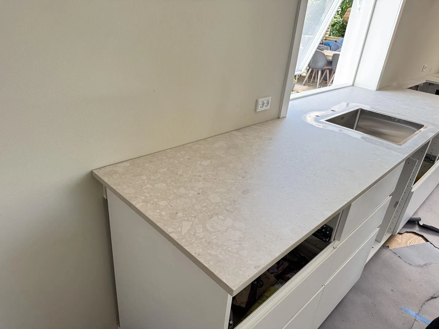 Köksbänkskiva i ljus matt Dekton Ava, 20 mm, monterad på vita köksstommar vid fönster i Hvidovre.