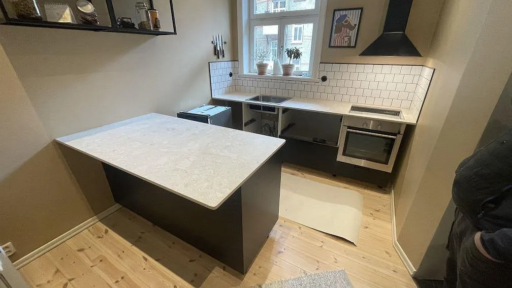 Köksbänkskiva i ljus matt Dekton Ava keramik, 20 mm, med större arbetsyta och väggbänk i ett kompakt kök i Malmö.