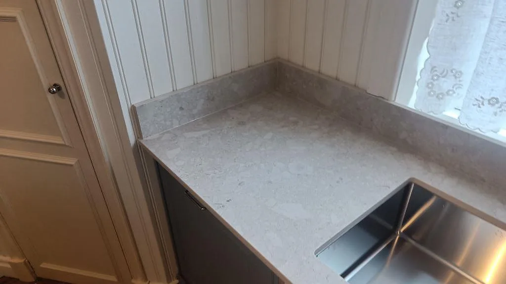 Hörn av köksbänkskiva i matt Dekton Ava, keramik, med uppvikt stänkkant och synlig kantprofil i Nässjö.