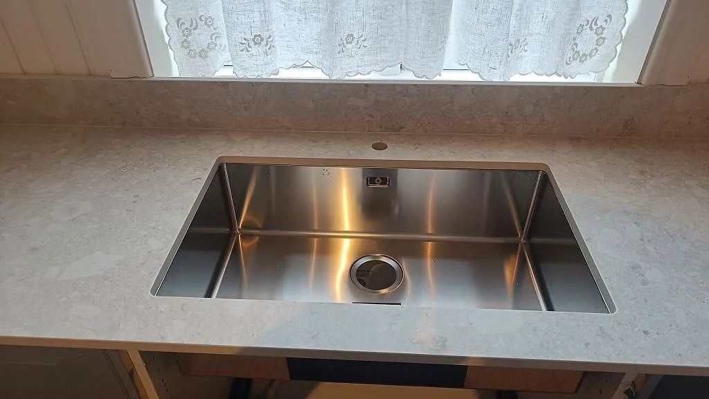 Köksbänkskiva i matt Dekton Ava, keramik, vid diskhozonen och stänkkant under fönster i Nässjö.