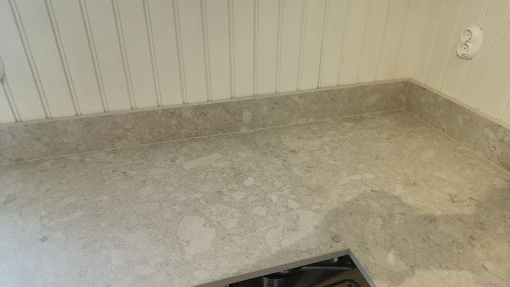 Detalj av väggbänkskiva i matt Dekton Ava, keramik, med stänkkant och öppet urtag i Nässjö.