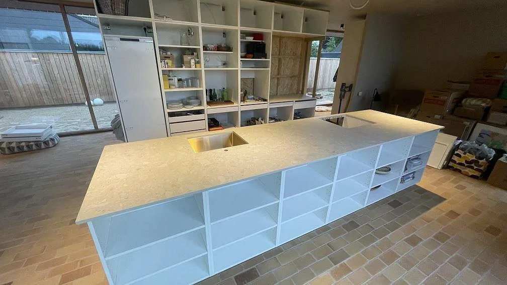 Köksö med matt 20 mm bänkskiva i Dekton Ava, diskho och hällurtag i ett kök under montering i Randers NØ.