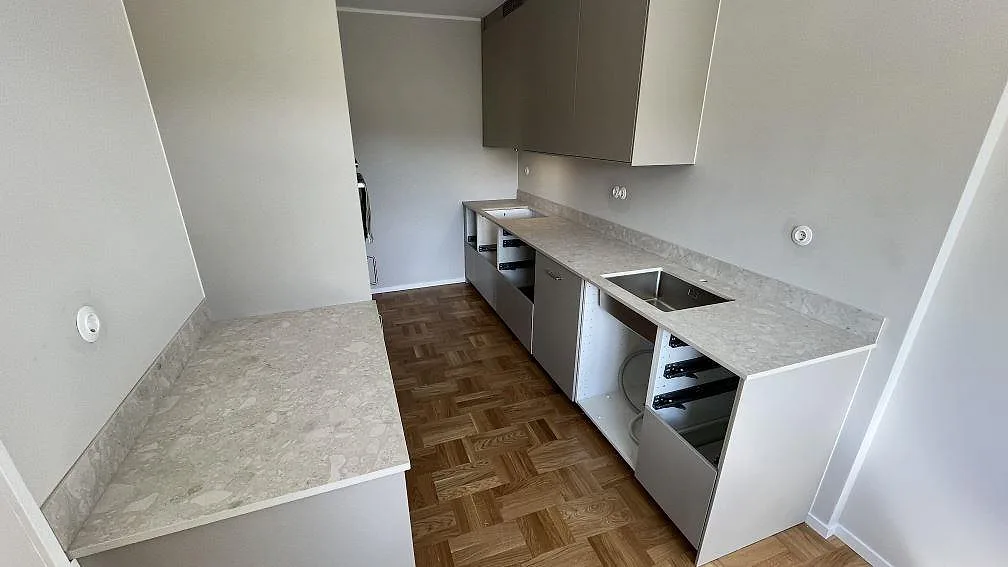 Köksbänkskiva i matt Dekton Ava, keramik, med låg stänkkant och synlig diskhoöppning i ett kök i Solna under montering.