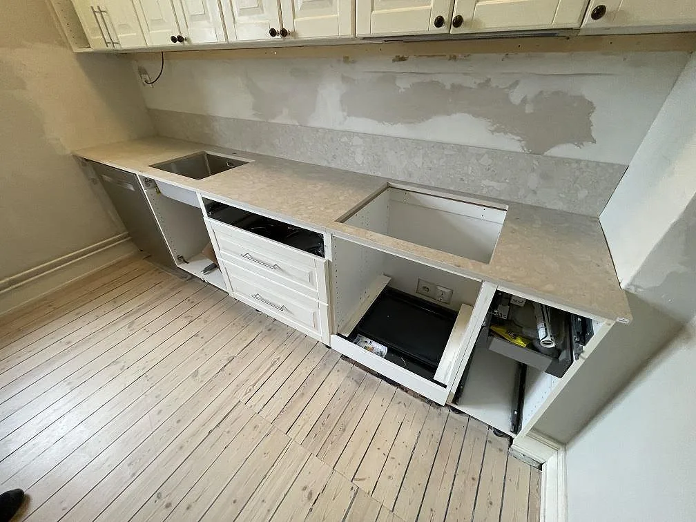 Köksbänkskiva i matt Dekton Ava med låg stänkkant, rostfri diskho och hällöppning i ett kök under montering i Stockholm.